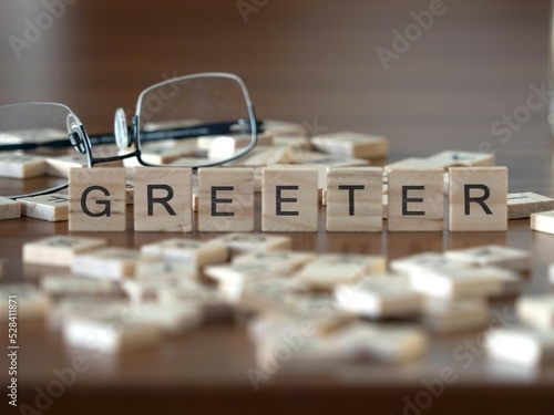 greeter word or concept represented by wooden letter tiles on a wooden table with glasses and a book photo