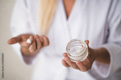 Fototapeta A woman in a white robe with a face cream