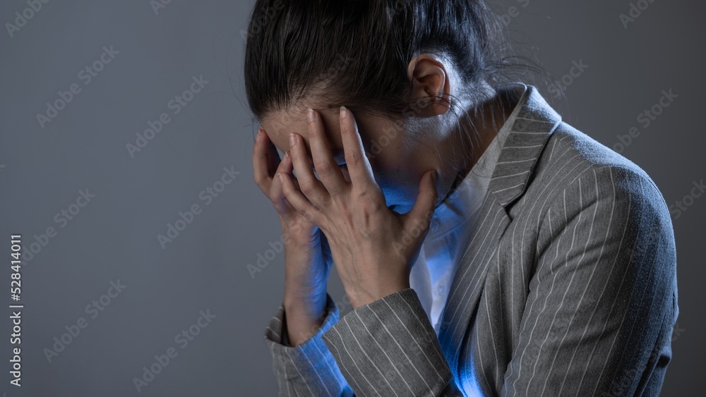 Despair and headache, problems at work and in business, experiencing a crisis. young woman in a business suit standing clutching head, portrait on a gray background Despair and headache, problems at work and in business, experiencing a crisis. young woman in a business suit standing clutching head, portrait on a gray background