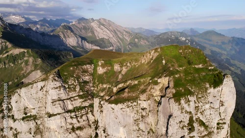 Aerial view of Niederbauen Chulm on a golden summer morning in the Swiss Alps with a spinning view from the peak's cliffs towards the fjords of Lake Lucerne, Uri, Mythen and the rising sun photo