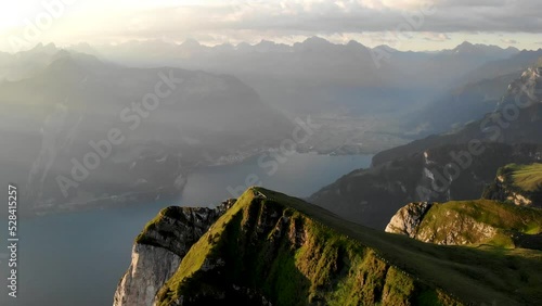 Aerial flyover over the summit of Niederbauen Chulm with Lake Lucerne, Uri and lakeside fjords and cliffs in view on a golden summer morning in the Swiss Alps photo