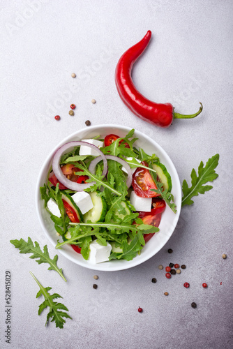 Healthy vegetarian salad with fresh arugula, cherry tomatoes, soft cheese and cucumbers