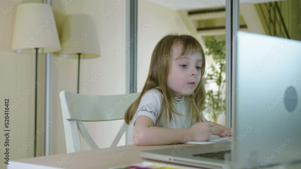 Distance Education Online Learning Lesson Concept. Cute PreSchool Kid Girl Drawing on Paper Using Laptop Computer for Homework at Home. Elearning Digital Native