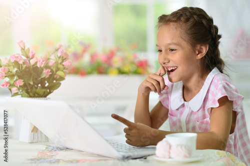 Portrait of beautiful little girl with laptop pointing