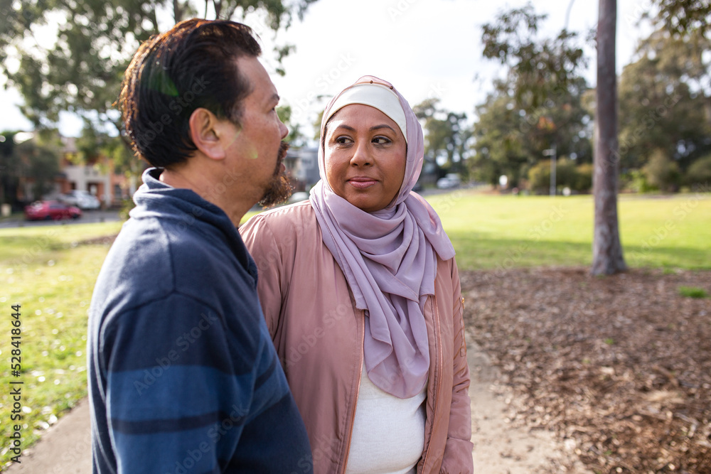 © Austockphoto - Middle aged woman wearing pink hijab looking at a middle aged man wearing blue sweater on a big lawn © Austockphoto - Middle aged woman wearing pink hijab looking at a middle aged man wearing blue sweater on a big lawn
