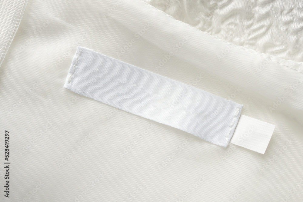 Blank white laundry care clothes label on fabric texture background Blank white laundry care clothes label on fabric texture background