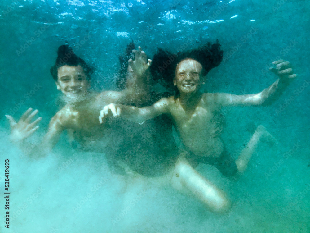 Mother and two boys playing together in ocean on calm day Mother and two boys playing together in ocean on calm day