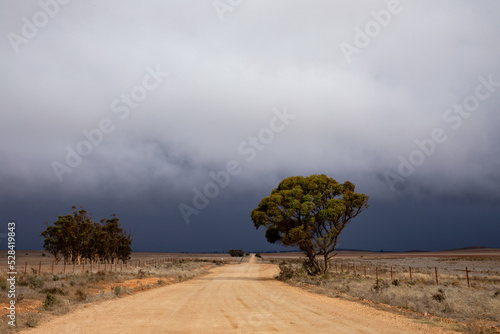 dirt road in rural landscape with approaching storm