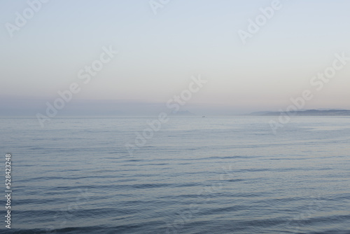 Beautiful seascape in a misty haze at sunset. Views of the Strait of Gibraltar at sunset. The sea surface is in a blurry focus.