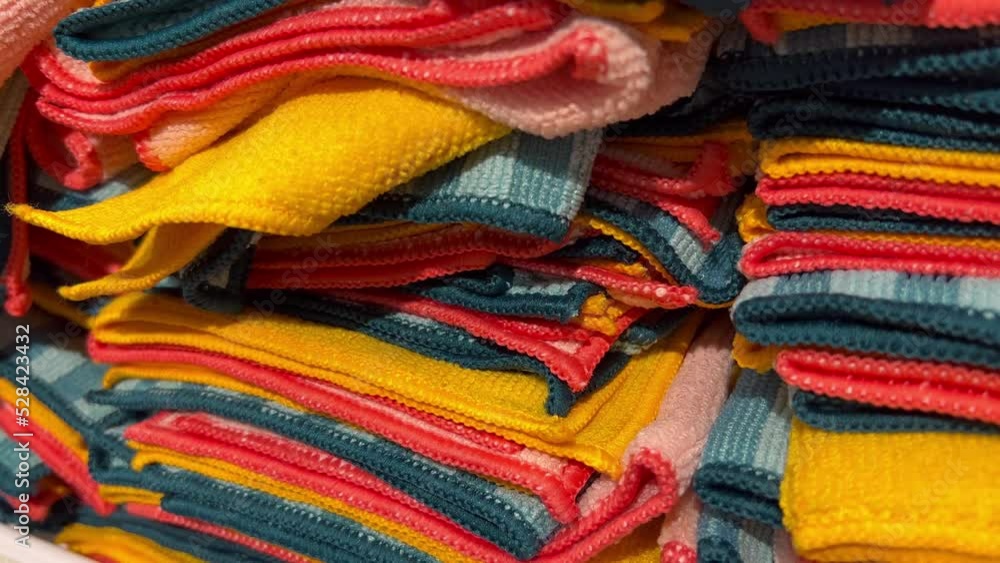 In the retail mall, cotton hand towels or towels in the colors red, yellow, green, grey, and white are stacked one on top of the other for sale. In the retail mall, cotton hand towels or towels in the colors red, yellow, green, grey, and white are stacked one on top of the other for sale.