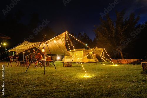 Canvas Print Outdoor camping tent with tarp or flysheet on grass courtyard and warm night light under dark night sky, family vacation picnic on holiday relax, Overview of camping of family tourist