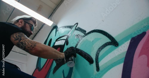 Graffiti artist painting on gallery wall. handheld camera