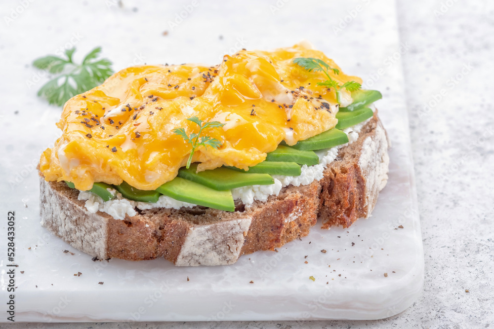 Scrambled eggs with avocado and cream cheese on toast. Breakfast food Scrambled eggs with avocado and cream cheese on toast. Breakfast food