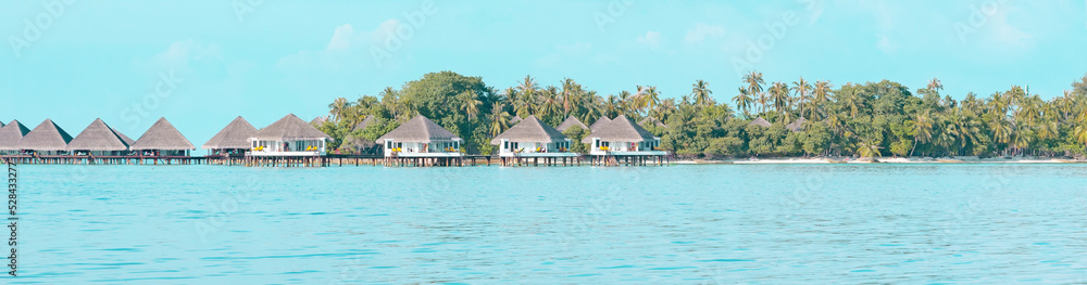 view from sea to island and water villas at day time with blue sky and beautiful clouds in the Maldives, the concept of luxury travel, banner