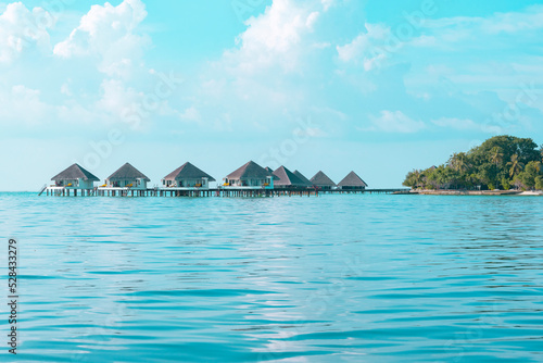 Fototapeta Naklejka Na Ścianę i Meble -  view from sea to island and water villas at day time with blue sky and beautiful clouds in the Maldives, the concept of luxury travel