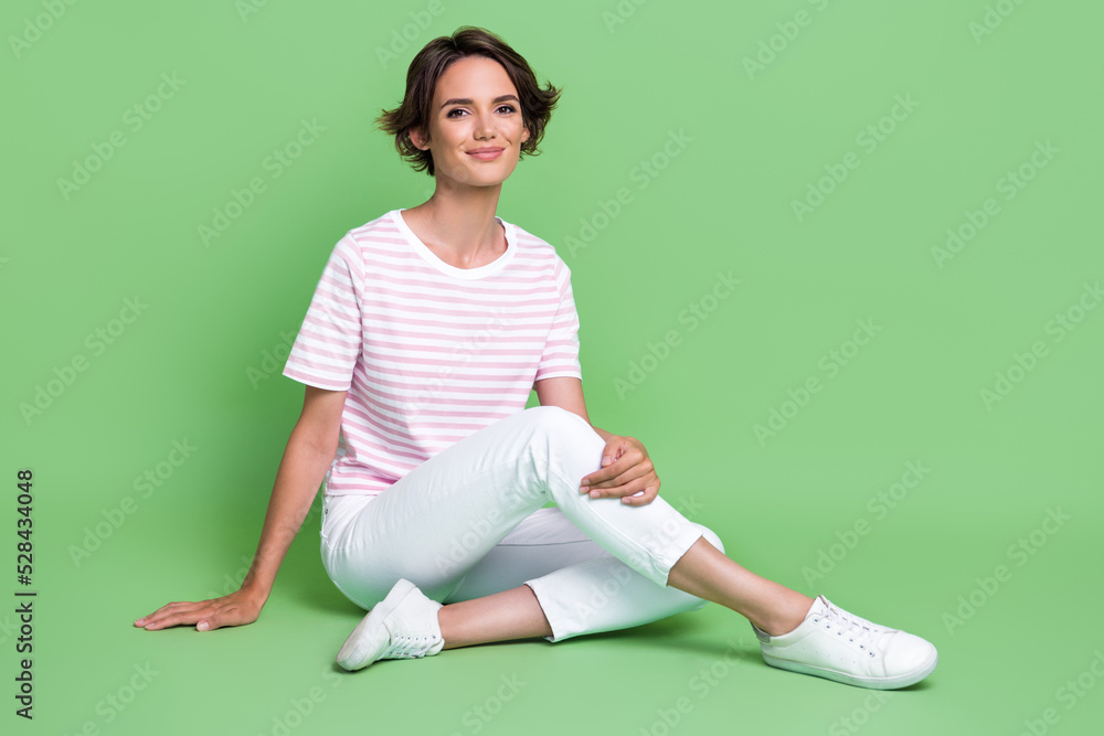 Photo of pretty cute lady dressed nice clothes outfit sit floor relax rest good mood free time isolated on green color background Photo of pretty cute lady dressed nice clothes outfit sit floor relax rest good mood free time isolated on green color background