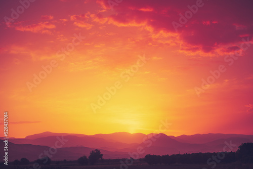 Amazing bright orange sunset over mountain range. Beautiful nature scenery background. Tourism and travel concept image. Copy space.