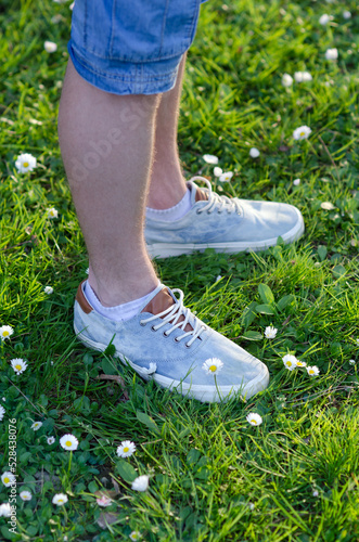 Legs of teenage boy standing on the meadow grass on a sunny spring day