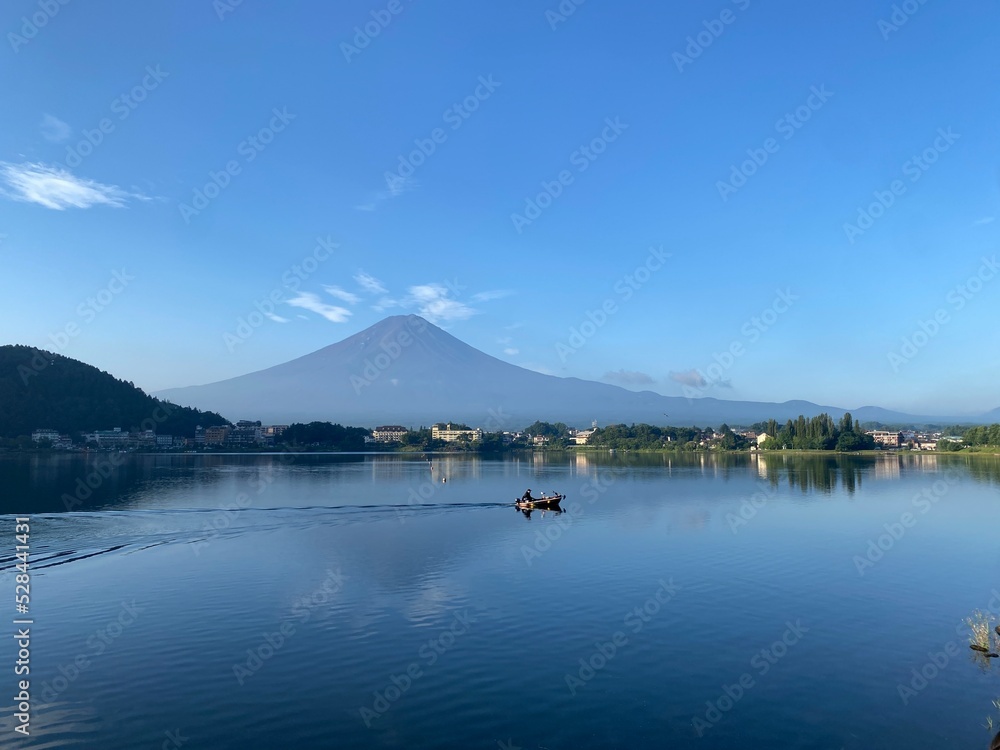 Boat ride across the lake Kawaguchiko with beautiful clear Mt. Fuji view, sunny day with blue sky and the clear tip of the mountain, year 2022 August 27th, 6:27am Yamanashi prefecture, Japan

