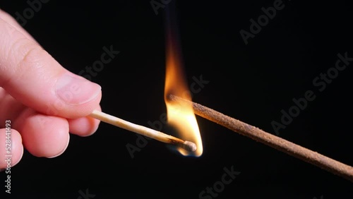 Man lighting incense stick on black background, closeup