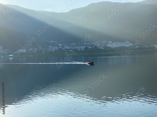 Boat riding through the lake of Kawaguchiko in the early morning after 6am, the sun hits the water, year 2022 August 27th, Yamanashi prefecture