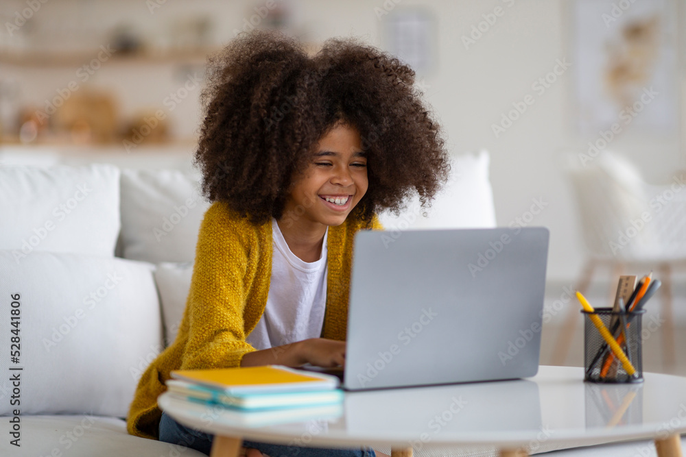 Smiling black school girl doing homework, using computer Smiling black school girl doing homework, using computer