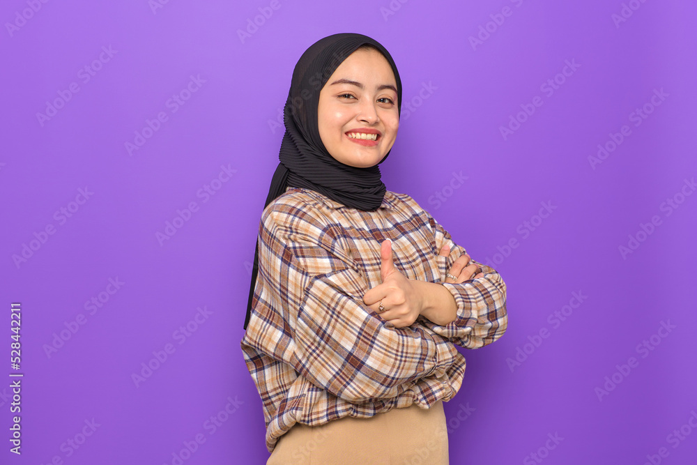 Cheerful young Asian woman in plaid shirt showing thumbs up isolated on purple background Cheerful young Asian woman in plaid shirt showing thumbs up isolated on purple background