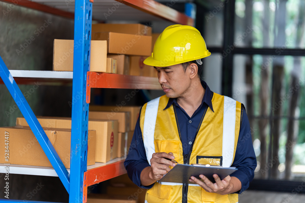 Portrait of middle aged asian warehouse worker standing in large warehouse distribution center. Portrait of middle aged asian warehouse worker standing in large warehouse distribution center.