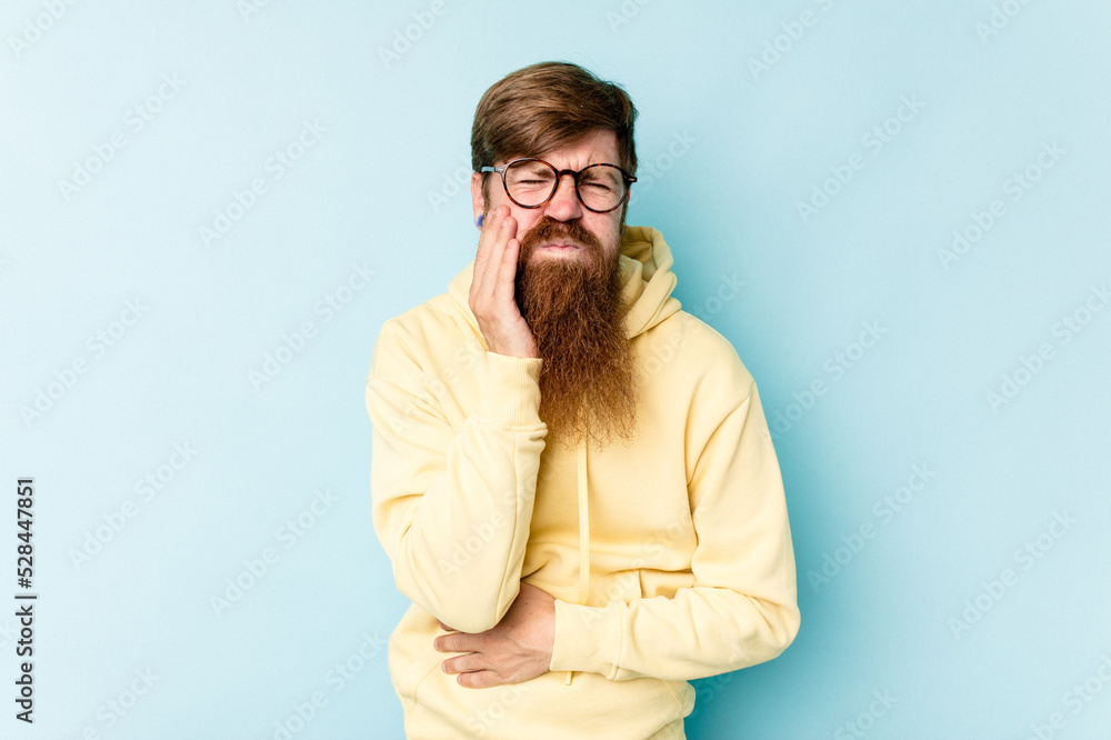 Young caucasian red-haired man isolated on blue background blows cheeks, has tired expression. Facial expression concept. Young caucasian red-haired man isolated on blue background blows cheeks, has tired expression. Facial expression concept.