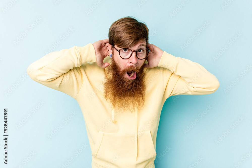 Young caucasian red-haired man isolated on blue background screaming, very excited, passionate, satisfied with something. Young caucasian red-haired man isolated on blue background screaming, very excited, passionate, satisfied with something.