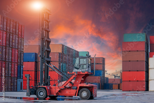 Crane lifting up container and unloading cargo into the import-export zone in yard.