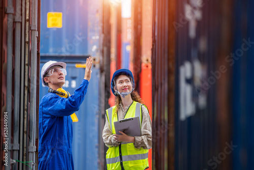 Engineer wearing industrial work wear and protective helmet doing stock tick check the transportation of goods in container yard,Import export shipping concept.
