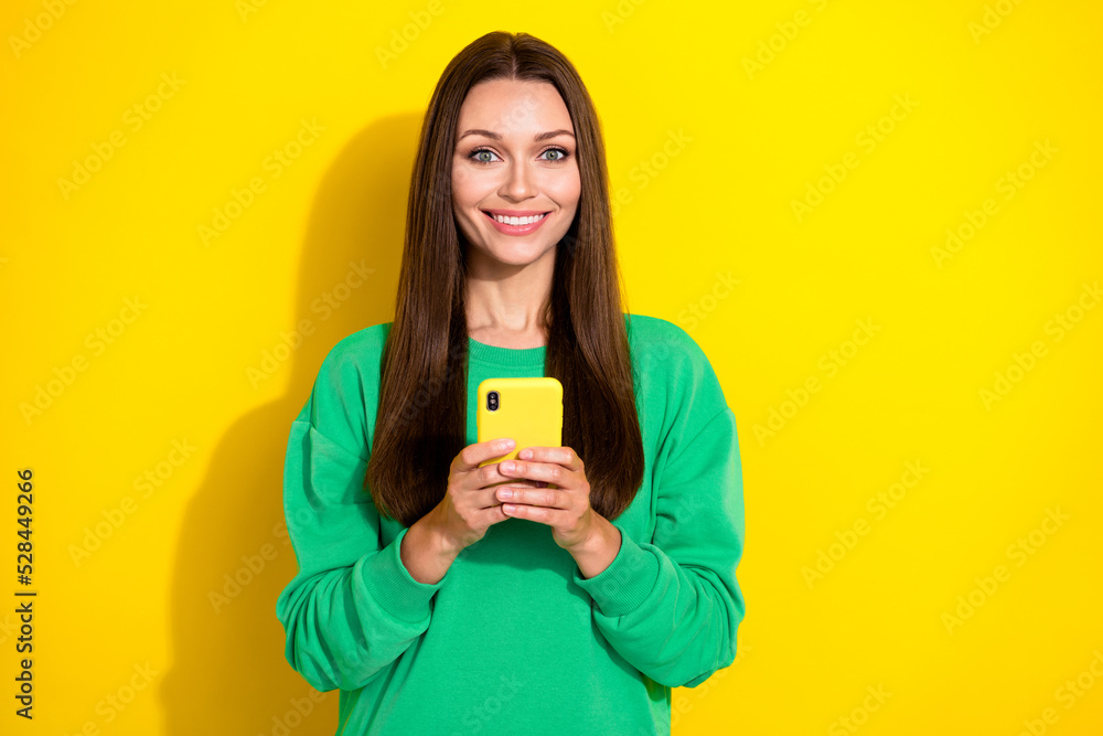 Photo portrait of charming young lady holding telephone chatting friends wear stylish green sportswear isolated on yellow color background Photo portrait of charming young lady holding telephone chatting friends wear stylish green sportswear isolated on yellow color background