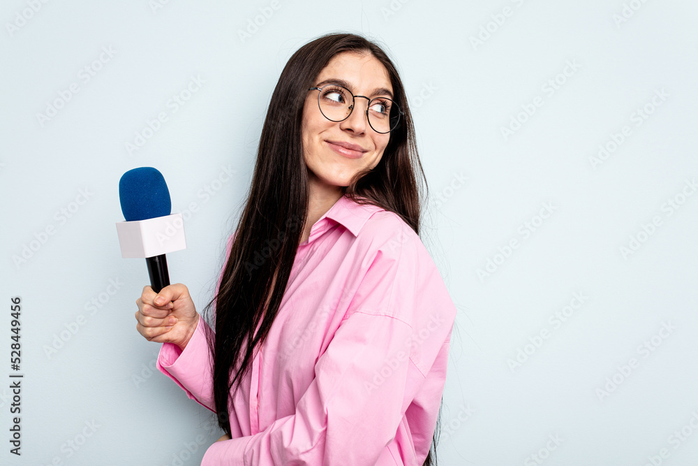 Young caucasian tv presenter woman isolated on blue background looks aside smiling, cheerful and pleasant. Young caucasian tv presenter woman isolated on blue background looks aside smiling, cheerful and pleasant.