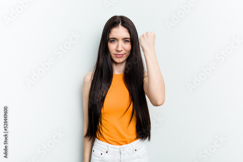 Young caucasian woman isolated on white background showing fist to camera, aggressive facial expression.