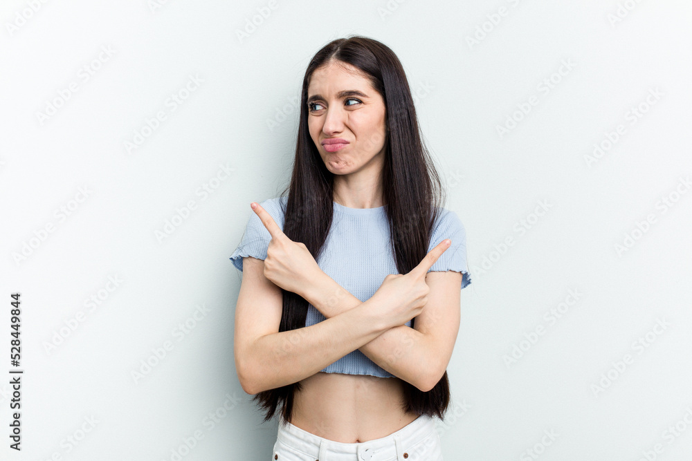 Young caucasian woman isolated on white background points sideways, is trying to choose between two options. Young caucasian woman isolated on white background points sideways, is trying to choose between two options.