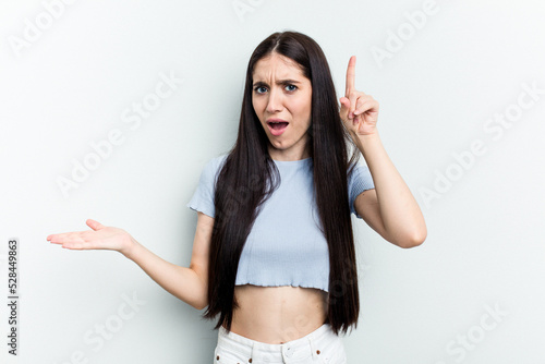 Young caucasian woman isolated on white background holding and showing a product on hand.