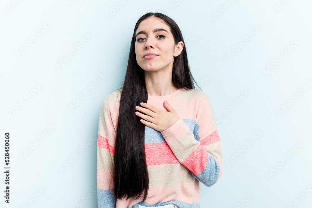 Young caucasian woman isolated on blue background taking an oath, putting hand on chest. Young caucasian woman isolated on blue background taking an oath, putting hand on chest.