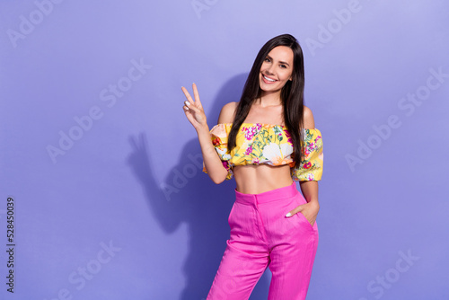 Photo of pretty cute lady wear yellow crop top showing v-sign empty space isolated violet color background
