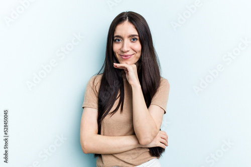 Young caucasian woman isolated on blue background suspicious, uncertain, examining you. © Asier