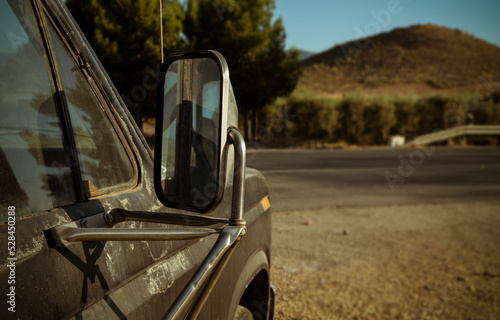Closeup of side mirror of an old, dirty truck