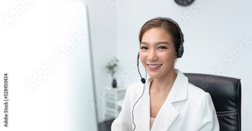 Asian woman Call center agent with headset working on support hotline in modern office with copy space.