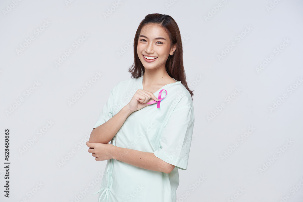 Happy asian woman patient showing pink badge ribbon chest to support breast cancer cause. breast cancer awareness concept. Happy asian woman patient showing pink badge ribbon chest to support breast cancer cause. breast cancer awareness concept.