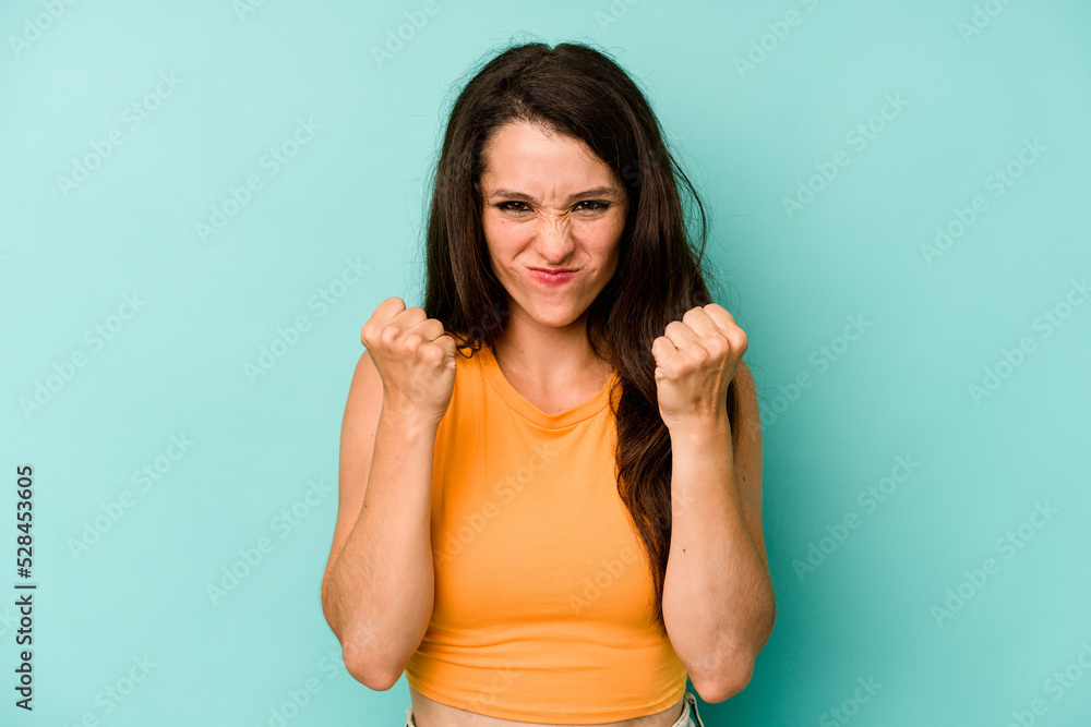 Young caucasian woman isolated on blue background upset screaming with tense hands. Young caucasian woman isolated on blue background upset screaming with tense hands.