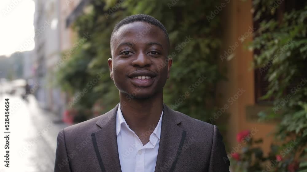 Close up portrait of confident businessman in stylish suit standing on street. Handsome african man smiling and relaxing during a break outdoors. Close up portrait of confident businessman in stylish suit standing on street. Handsome african man smiling and relaxing during a break outdoors.