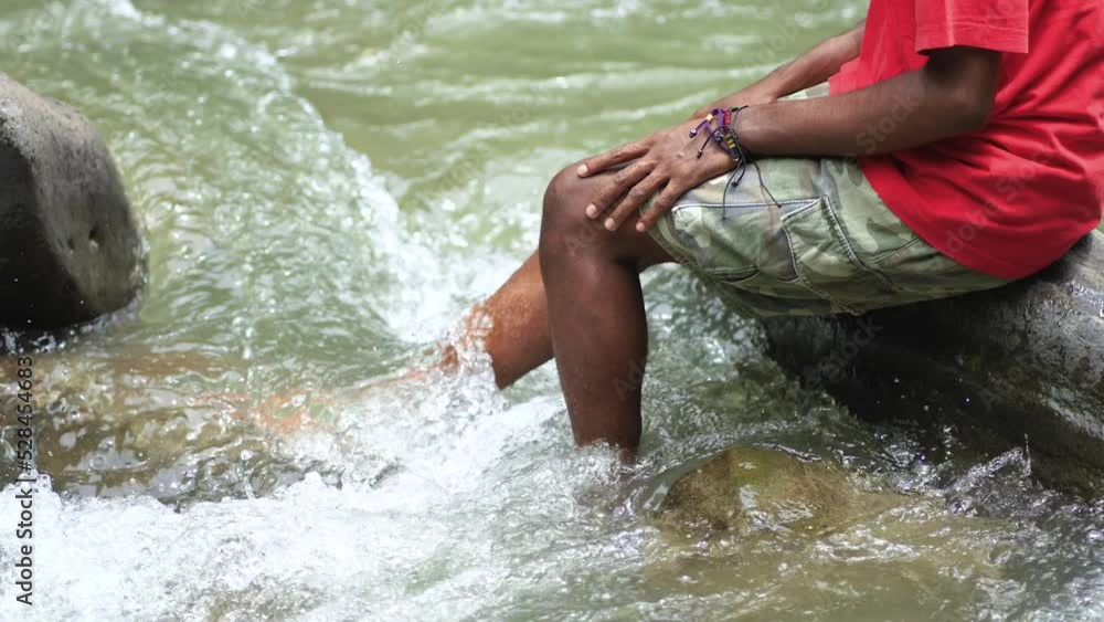 A Young Black Man Enjoying The Flow of Water With His Legs A Young Black Man Enjoying The Flow of Water With His Legs