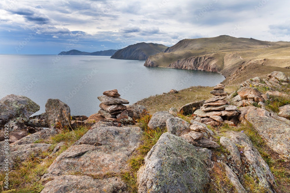 Autumn landscape of Baikal  Lake on a cloudy day in September. On the rocky shores of the lake, tourists built stone pyramids. Natural background