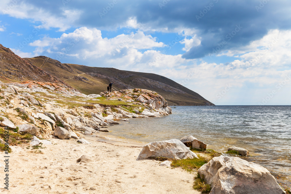Baikal Lake. Sandy beach and rocky shore in the shallow bay of Ust-Anga. Tourists travel along the coast and explore the surroundings Baikal Lake. Sandy beach and rocky shore in the shallow bay of Ust-Anga. Tourists travel along the coast and explore the surroundings