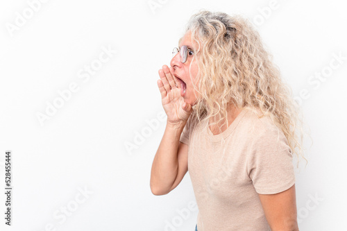 Middle age caucasian woman isolated on white background is saying a secret hot braking news and looking aside