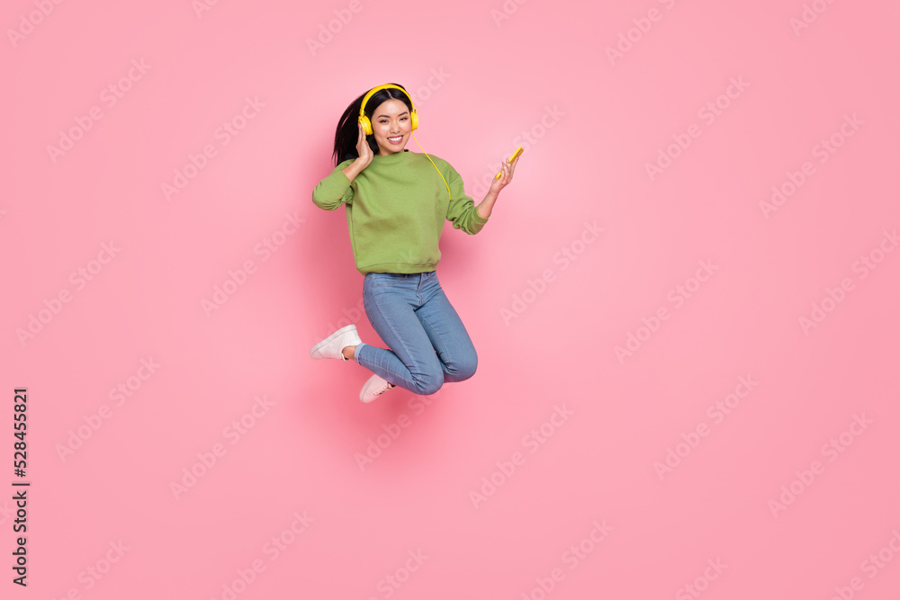 Full length photo of nice millennial lady jump listen music wear pullover jeans sneakers isolated on pink background